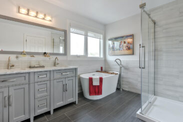 Photo of a newly renovated master ensuite bathroom in an Edmonton area home featuring a freestanding tub, custom vanity and shower. Lots of natural light, highlighting the contrasting wall and floor tile