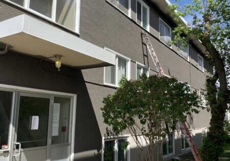 8 Exterior of a low rise apartment with grey stucco and white window trim